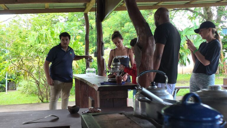 Guests taking turns at a hand grinder with their guide on a chocolate and coffee tour in Costa Rica