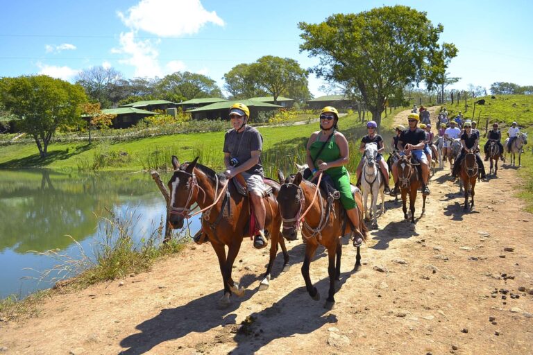 Guests in helmets on a horseback ride along a pond at Rincón de la Vieja, Guanacaste, Costa Rica