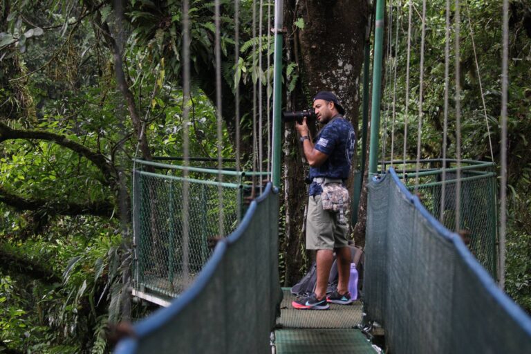 Wildlife photographer with a telephoto lens on a hanging bridge platform in the rainforest near Tenorio Volcano, Costa Rica