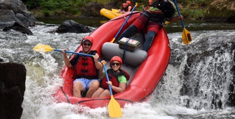 Smiling couple in helmets paddling a red raft through the rapids of the Tenorio River, Costa Rica
