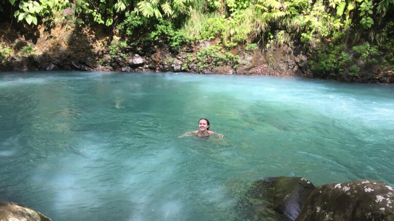 Guest swimming in the turquoise water of Río Celeste in the rainforest near Bijagua, Costa Rica