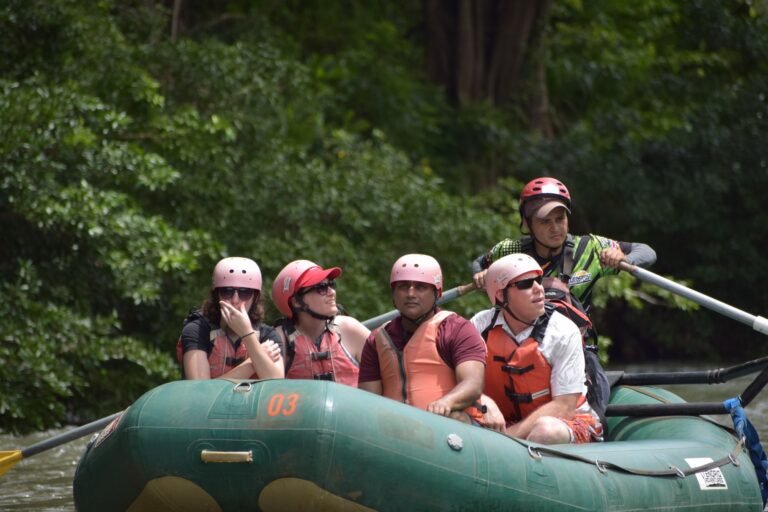 Group in a raft watching wildlife along the riverbank with their guide on a safari float in Guanacaste, Costa Rica