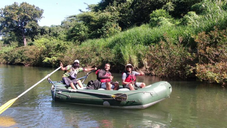 Guests and their guide smiling in a raft on a calm river during a safari float in Guanacaste, Costa Rica
