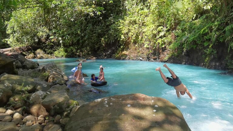 Guests swimming and diving into the turquoise water of Río Celeste at a private property near Bijagua, Costa Rica