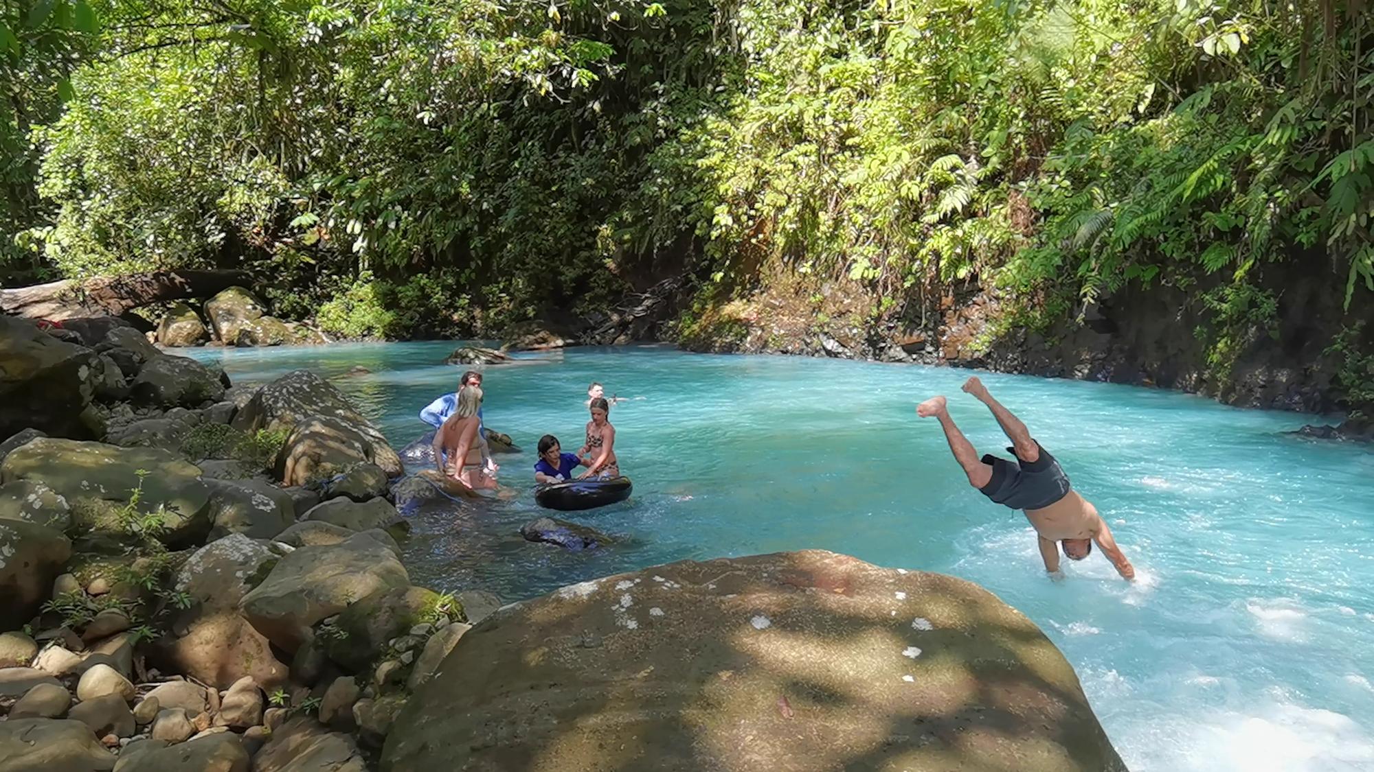 Guests swimming and diving into the turquoise water of Río Celeste at a private property near Bijagua, Costa Rica