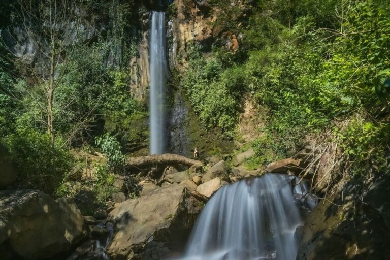 Tall, thin waterfall falling down a rock wall in the forest at Rincón de la Vieja, Guanacaste, Costa Rica
