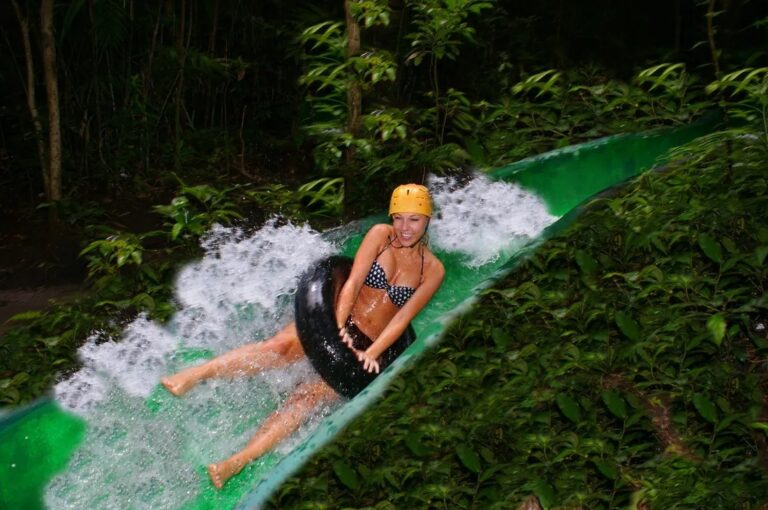 Guest riding an inner tube down a green mountain waterslide through the forest at Rincón de la Vieja, Costa Rica