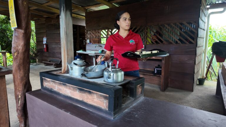 Host preparing drinks on a traditional wood-fired stove at a coffee and cacao farm in Costa Rica