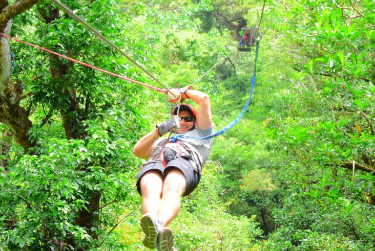 Smiling guest in a red helmet on a zip line through the forest at Rincón de la Vieja, Costa Rica