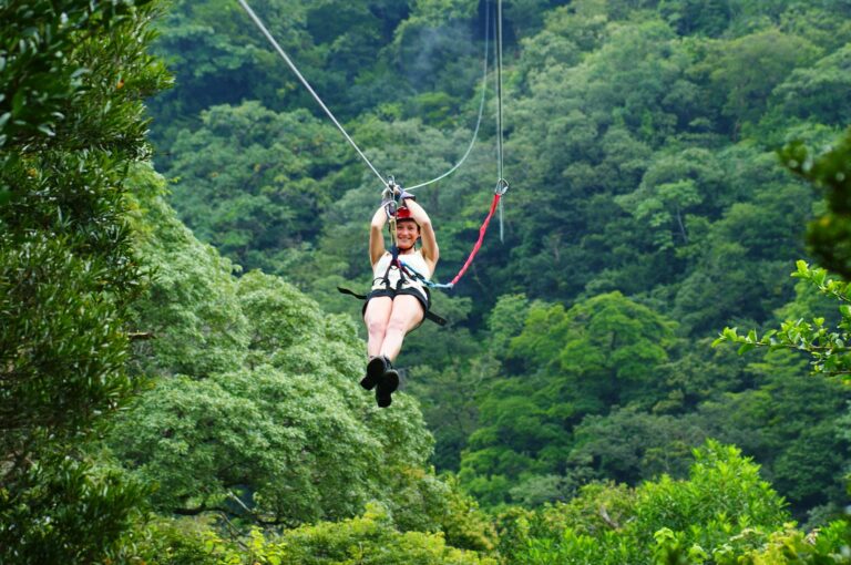 Smiling guest in a helmet and harness on a zip line above the forest canopy at Rincón de la Vieja, Guanacaste, Costa Rica