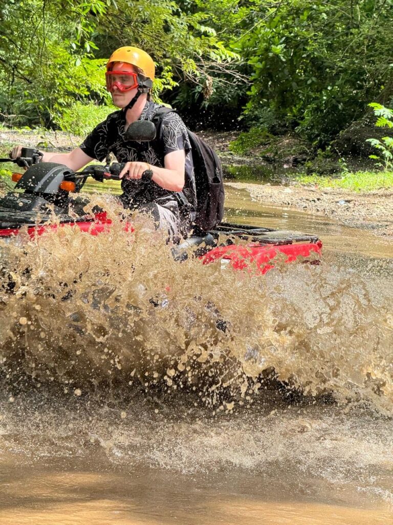 Close-up of an ATV rider with goggles in the middle of a river splash