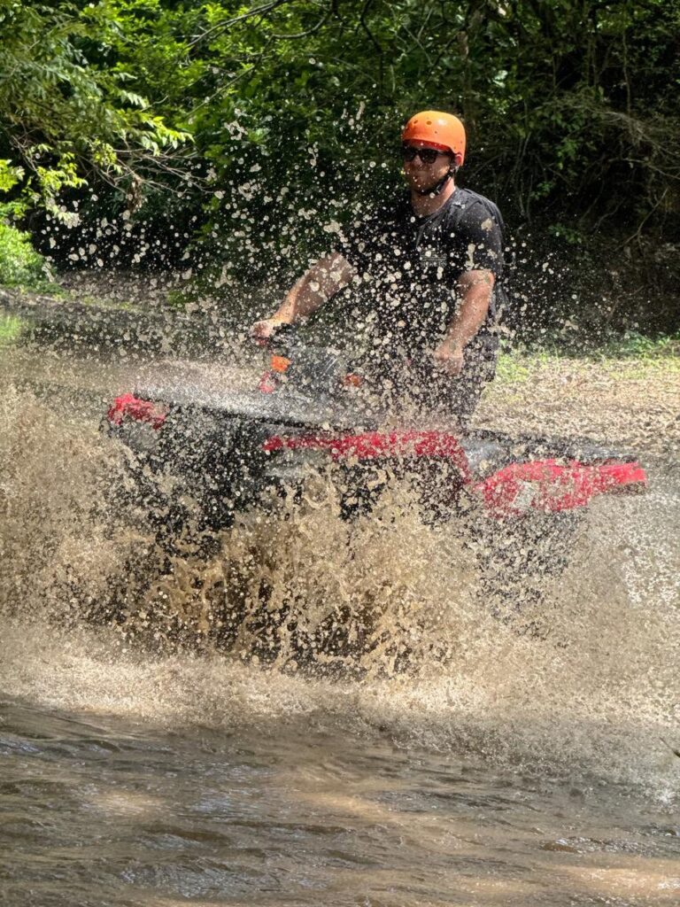 ATV rider in a helmet splashing through a river on a tour in Guanacaste