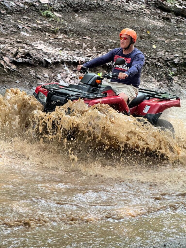 Rider on a red Honda ATV crossing a muddy river in Guanacaste, Costa Rica