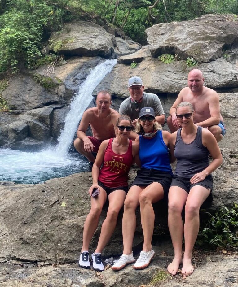 Group of guests sitting on the rocks beside a small waterfall during an ATV tour