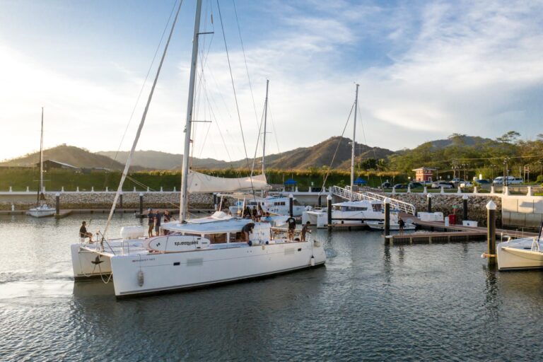 Catamaran with guests on deck pulling into Flamingo Marina at golden hour, Guanacaste, Costa Rica