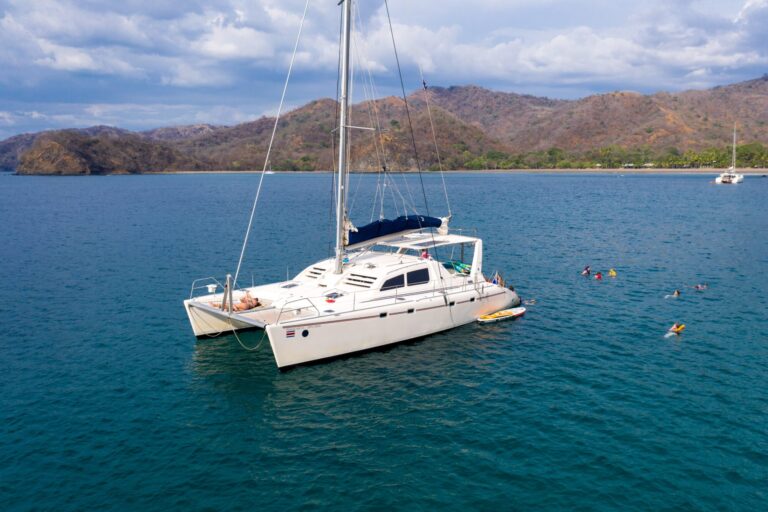 Guests swimming and snorkeling beside the anchored catamaran in a wide bay in Guanacaste, Costa Rica