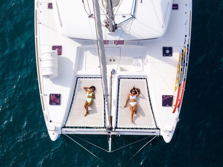 Aerial view of two guests relaxing on the catamaran trampoline nets over deep blue water, Guanacaste, Costa Rica
