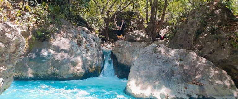 Guest jumping from the rocks into a blue pool on the Río Blanco