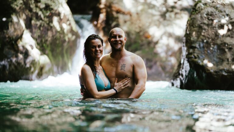 Couple smiling in the clear water of the Río Blanco near La Leona Waterfall