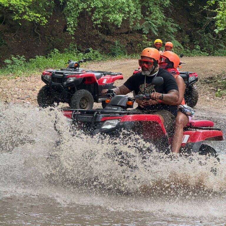 Couple on a double ATV crossing a river while the rest of the group waits behind