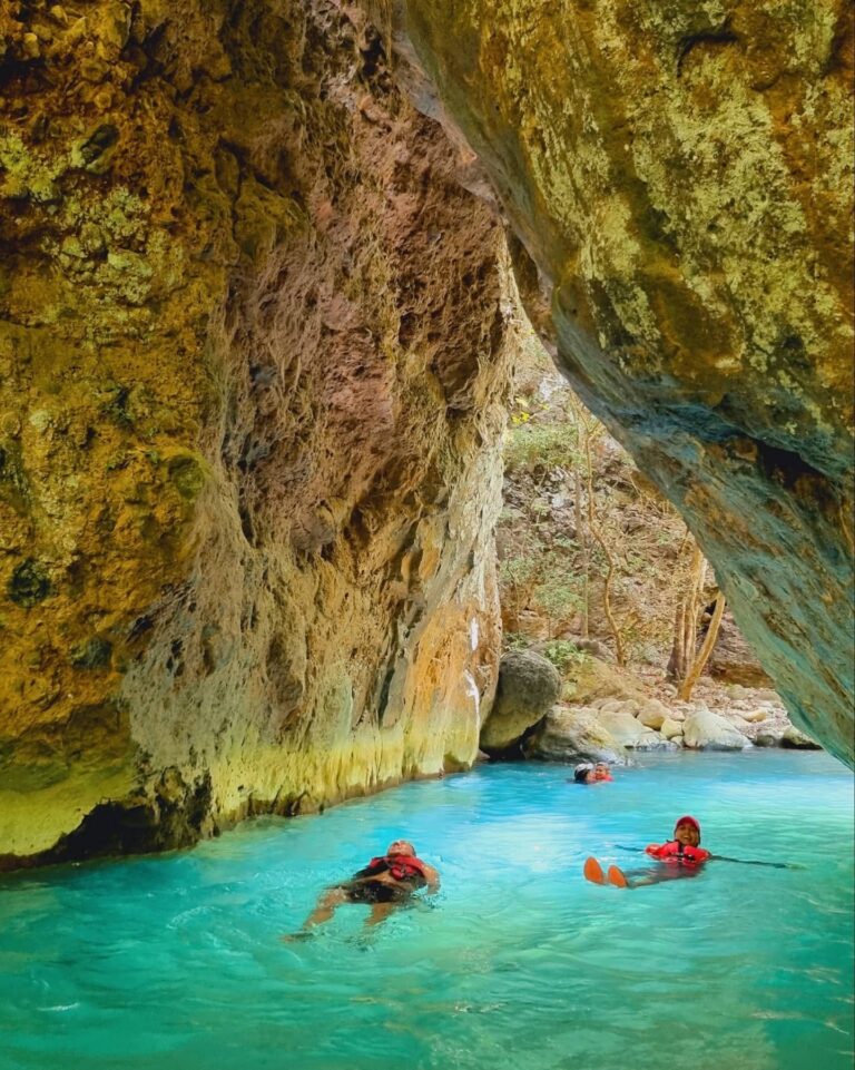 Guests in life jackets floating in a turquoise pool under the canyon walls of the Río Blanco