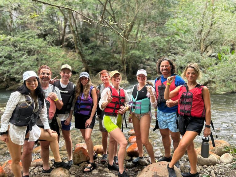 Group of guests in life jackets posing on the bank of the Río Blanco during the La Leona hike