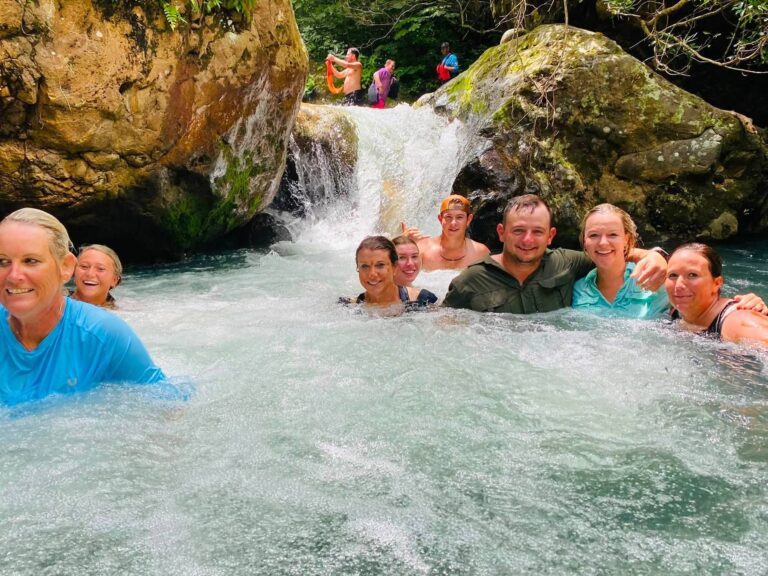 Group of guests swimming below a small waterfall on the Río Blanco