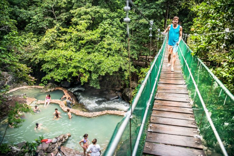 Guest crossing the hanging bridge above the Río Negro hot spring pools, Rincón de la Vieja, Costa Rica
