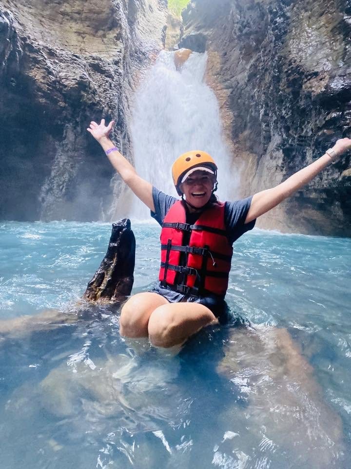 Guest in a helmet and life jacket celebrating in front of La Leona Waterfall