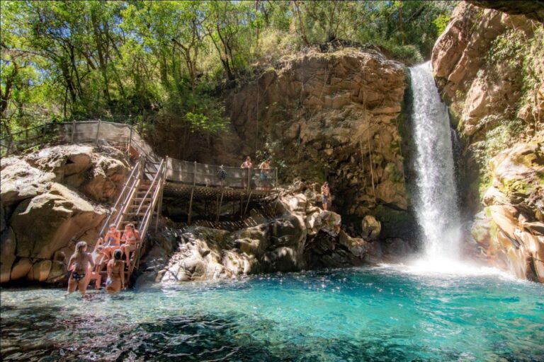 Oropéndola Waterfall falling into its turquoise pool, with guests on the stairs and platform, Rincón de la Vieja, Costa Rica