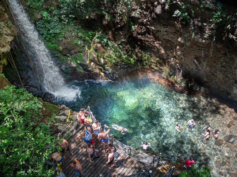 Guests swimming in the turquoise pool of Oropéndola Waterfall seen from above, Rincón de la Vieja, Costa Rica