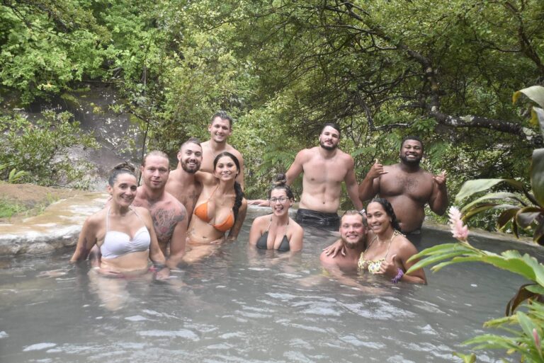 Group of guests smiling in a Río Negro hot spring pool under the trees, Rincón de la Vieja, Costa Rica