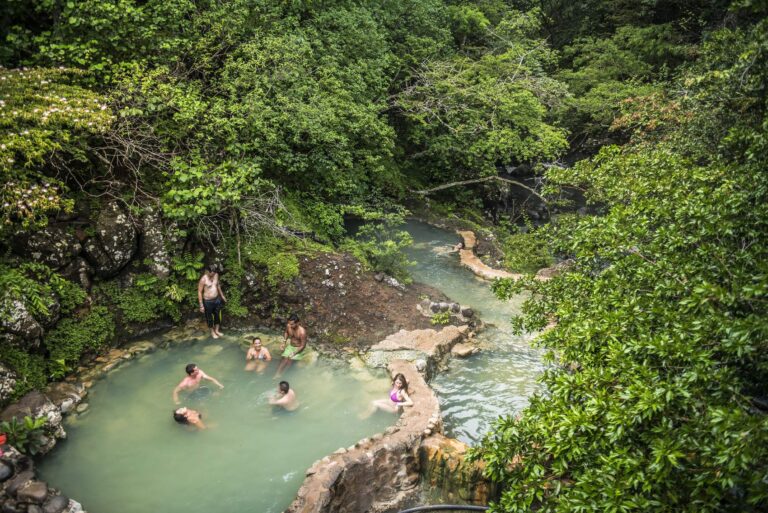Guests relaxing in a natural hot spring pool beside the Río Negro, surrounded by forest, Rincón de la Vieja, Costa Rica