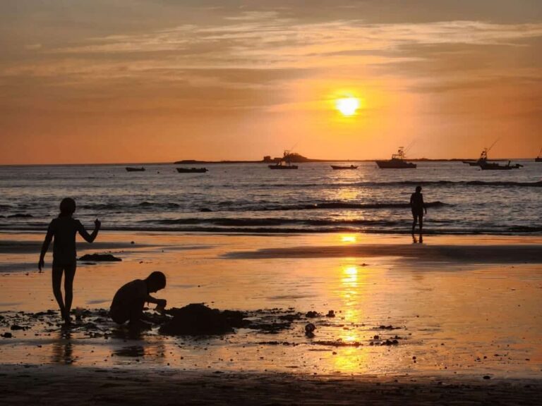 Sunset at Tamarindo Beach with fishing boats on the water and people on the sand