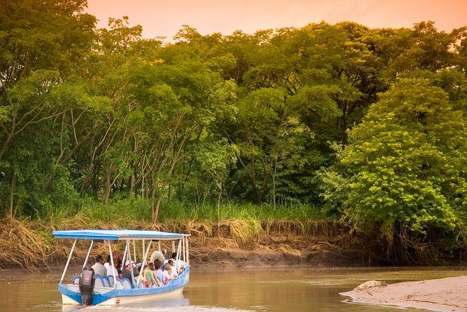 Covered tour boat with guests on the Tempisque River beside the riverside forest of Palo Verde, Costa Rica