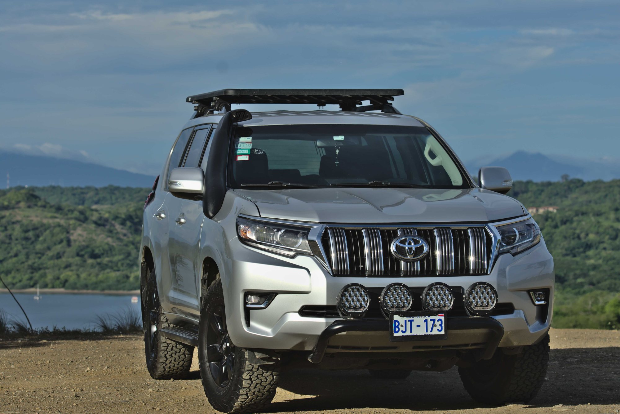 Toyota Land Cruiser Prado 4x4 parked on a hilltop with a bay view in Guanacaste