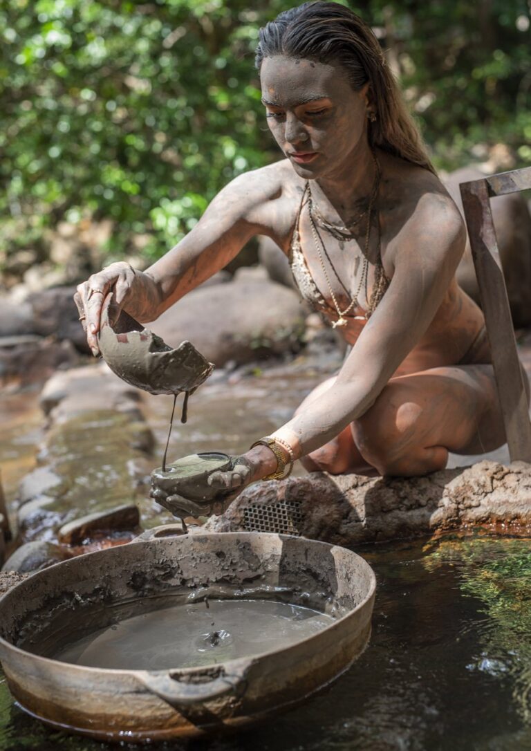 Guest covered in volcanic mud pouring warm mud from a clay bowl at the Río Negro hot springs, Costa Rica