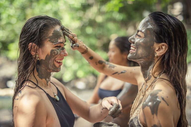 Two guests laughing while putting volcanic mud on their faces at the Río Negro hot springs, Rincón de la Vieja, Costa Rica
